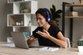 Hispanic female interpreter in headset working remotely talk use laptop