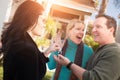 Hispanic Female Real Estate Agent Handing Over New House Keys to Happy Couple In Front of House Royalty Free Stock Photo