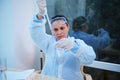 Hispanic scientist pharmacologist using a glass graduated pipette, titling a chemical substance into a test tube