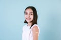 Hispanic girl child portrait after getting a vaccine protection and showing her arm with bandage receiving vaccination on blue bac Royalty Free Stock Photo