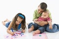 Hispanic girl coloring with brothers.