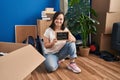 Hispanic girl with down syndrome sitting on the floor at new home winking looking at the camera with sexy expression, cheerful and Royalty Free Stock Photo