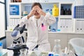 Hispanic girl with down syndrome working at scientist laboratory covering eyes with hands smiling cheerful and funny Royalty Free Stock Photo