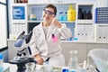 Hispanic girl with down syndrome working at scientist laboratory pointing with hand finger to face and nose, smiling cheerful Royalty Free Stock Photo