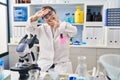 Hispanic girl with down syndrome working at scientist laboratory smiling cheerful playing peek a boo with hands showing face Royalty Free Stock Photo