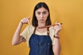 Hispanic girl eating healthy wooden spoon pointing down looking sad and upset, indicating direction with fingers, unhappy and