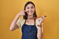 Hispanic girl eating healthy  wooden spoon pointing with hand finger to face and nose, smiling cheerful Royalty Free Stock Photo