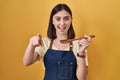 Hispanic girl eating healthy  wooden spoon pointing to you and the camera with fingers, smiling positive and cheerful Royalty Free Stock Photo