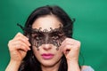 hispanic girl hiding behind Venetian mask on background green Royalty Free Stock Photo