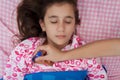 Hispanic girl sick with fever laying in bed Royalty Free Stock Photo