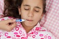 Hispanic girl sick with fever laying in her bed Royalty Free Stock Photo