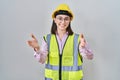 Hispanic girl wearing builder uniform and hardhat looking at the camera smiling with open arms for hug Royalty Free Stock Photo