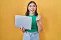 Hispanic girl working using computer laptop screaming proud, celebrating victory and success very excited with raised arms Royalty Free Stock Photo