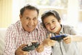 Hispanic Grandfather And Grandson Playing Video Game At Home