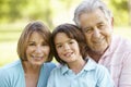 Hispanic Grandfather Relaxing With Grandchildren In Park