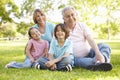 Hispanic Grandmother And Grandfather Relaxing With Grandchildren In Park