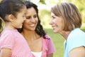 Hispanic Grandmother, Mother And Daughter Relaxing In Park