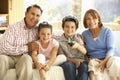 Hispanic Grandparents With Grandchildren Watching TV On Sofa At Home