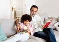 Hispanic Grandson Using Tablet Computer While Grandpa Reading Book Indoor Royalty Free Stock Photo