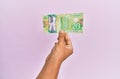 Hispanic hand holding 20 canadian dollars banknote over isolated pink background Royalty Free Stock Photo