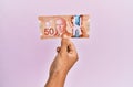 Hispanic hand holding 50 canadian dollars banknote over isolated pink background Royalty Free Stock Photo