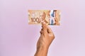 hispanic hand holding 100 canadian dollars banknote over isolated pink background Royalty Free Stock Photo