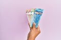 Hispanic hand holding canadian dollars banknotes over isolated pink background Royalty Free Stock Photo