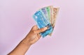 Hispanic hand holding canadian dollars banknotes over isolated pink background Royalty Free Stock Photo