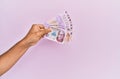 Hispanic hand holding 50 mexican pesos banknotes over isolated pink background