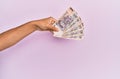 Hispanic hand holding 500 mexican pesos banknotes over isolated pink background