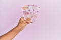 Hispanic hand holding 50 mexican pesos banknotes over isolated pink background