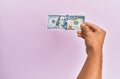 Hispanic hand holding 100 usa dollars banknote over isolated pink background Royalty Free Stock Photo