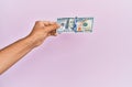 Hispanic hand holding 100 usa dollars banknote over isolated pink background Royalty Free Stock Photo
