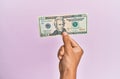 Hispanic hand holding 20 usa dollars banknote over isolated pink background Royalty Free Stock Photo