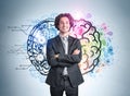 Hispanic handsome businessman in crossed arms pose wearing suit and pondering near light blue wall with colorful brain sketch with Royalty Free Stock Photo
