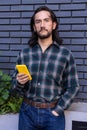 Hispanic male in his twenties holding a smartphone in his right hand