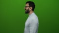 Hispanic man with beard and glasses in profile standing against a vibrant green background in a studio setting Royalty Free Stock Photo