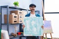 Hispanic man with beard holding canvas at at studio winking looking at the camera with sexy expression, cheerful and happy face Royalty Free Stock Photo