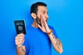 Hispanic man with beard holding italy passport hand on mouth telling secret rumor, whispering malicious talk conversation