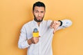 Hispanic man with beard holding reporter microphone with angry face, negative sign showing dislike with thumbs down, rejection Royalty Free Stock Photo