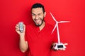 Hispanic man with beard holding solar windmill for renewable electricity and led bulb winking looking at the camera with sexy Royalty Free Stock Photo