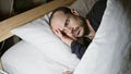 Hispanic man with beard lying in bed at home, looking tired or sleepless, in a dark bedroom setting at night Royalty Free Stock Photo