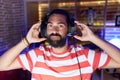 Hispanic man with beard playing video games wearing headphones relaxed with serious expression on face Royalty Free Stock Photo