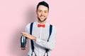 Hispanic man with beard preparing cocktail mixing drink with shaker smiling with a happy and cool smile on face