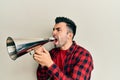 Hispanic man with beard screaming with vintage megaphone Royalty Free Stock Photo