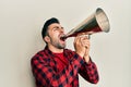 Hispanic man with beard screaming with vintage megaphone Royalty Free Stock Photo