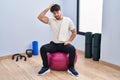 Hispanic man with beard sitting on pilate balls at yoga room confuse and wonder about question Royalty Free Stock Photo