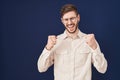 Hispanic man with beard standing over blue background excited for success with arms raised and eyes closed celebrating victory Royalty Free Stock Photo