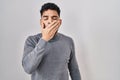 Hispanic man with beard standing over white background bored yawning tired covering mouth with hand Royalty Free Stock Photo
