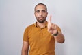 Hispanic man with beard standing over white background pointing with finger up and angry expression, showing no gesture Royalty Free Stock Photo